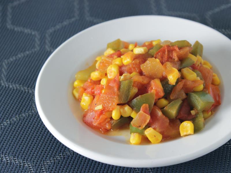 cooked vegetables in a white dish-tomatoes, corn, and green pepper